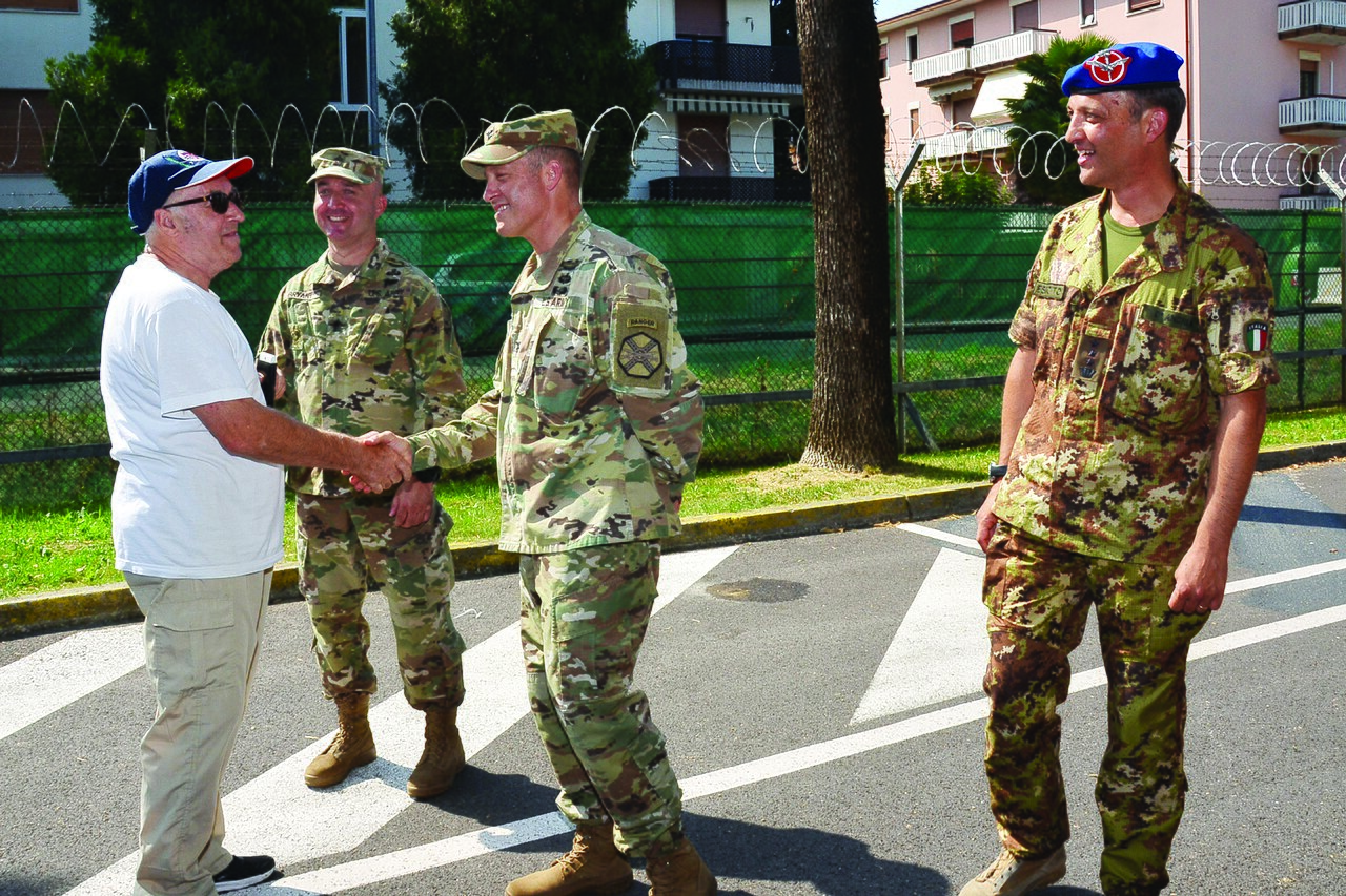Soldiers greet a visiting veteran on a tree-lined street on Caserma Ederle